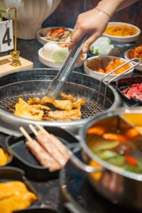 Delight in a vibrant Korean BBQ setup with various dishes and grilling meats indoors.