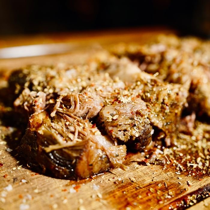 Close-up of seasoned, tender, slow-cooked pulled pork on a rustic wooden board, ready to serve.